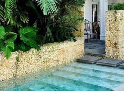 The Strand TCI real estate design inspiration featuring a beautiful aqua pool with natural stone and native greenery.