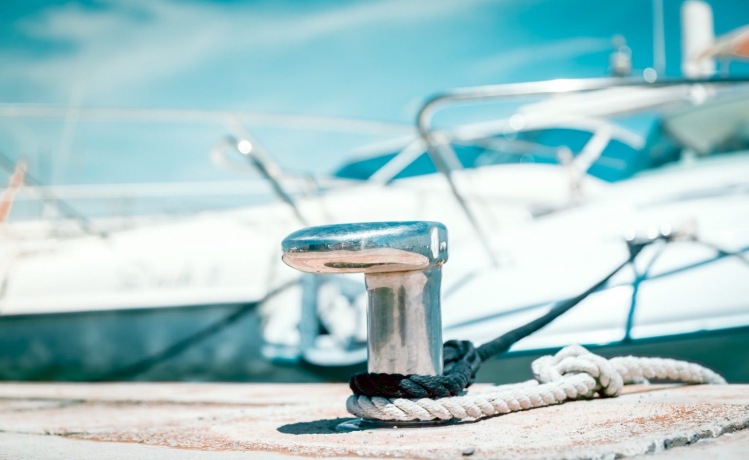 close up of round cleet in marina with boat in background