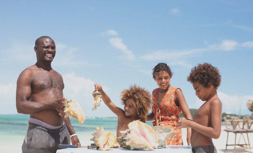 The Strand Turks and Caicos - family enjoying their beach vacation while admiring conch shells