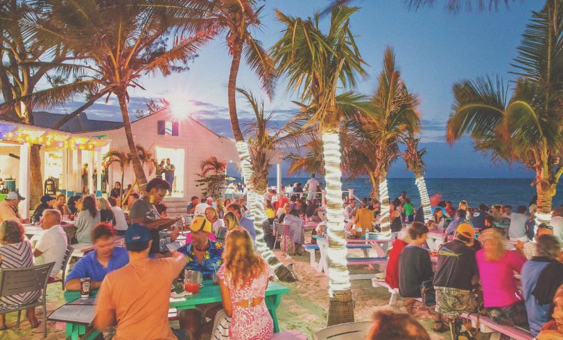 wide shot of outdoor restaurant on the ocean with palm trees - looks like they're having fun!