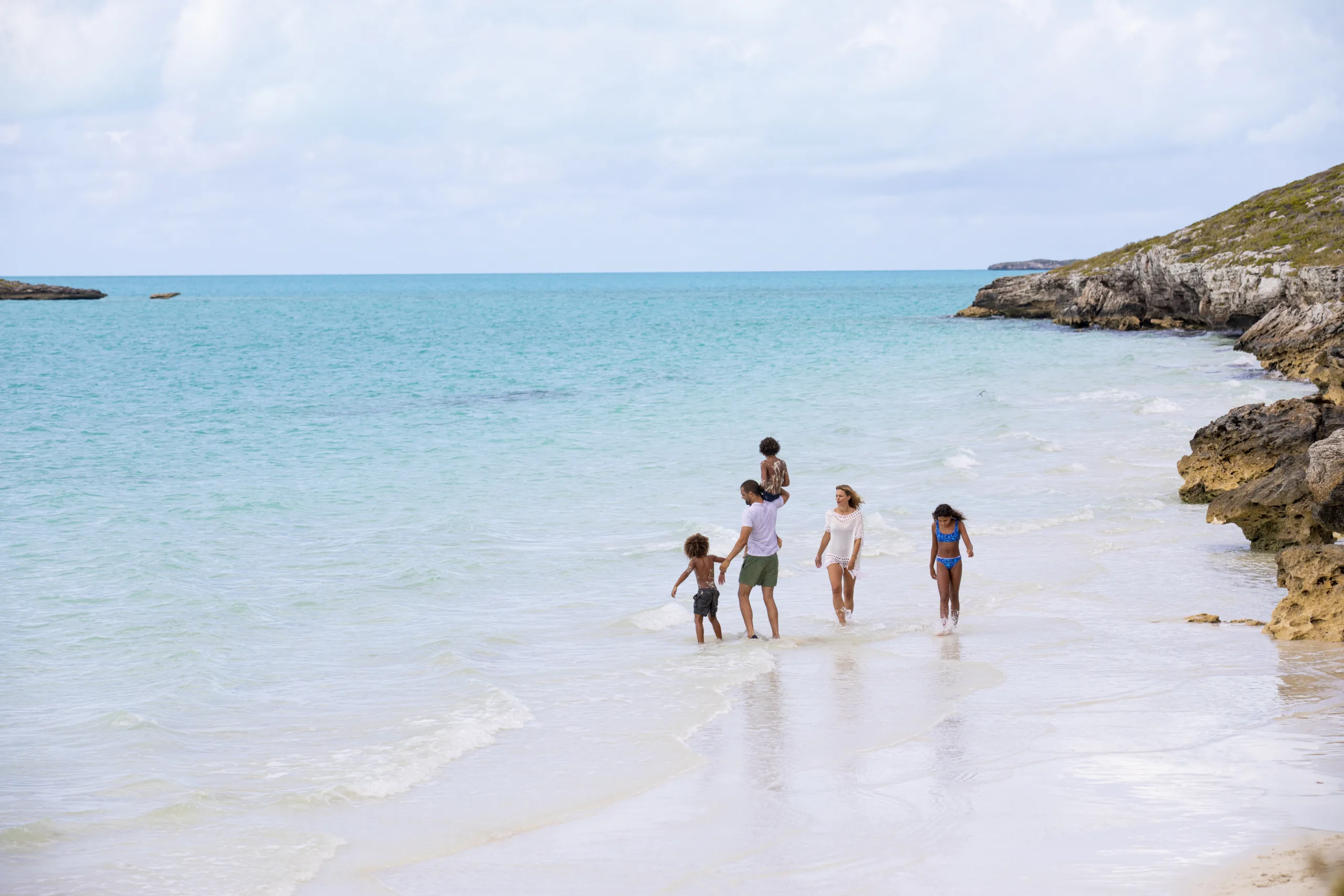 Family walking on Caicos Banks at The Strand